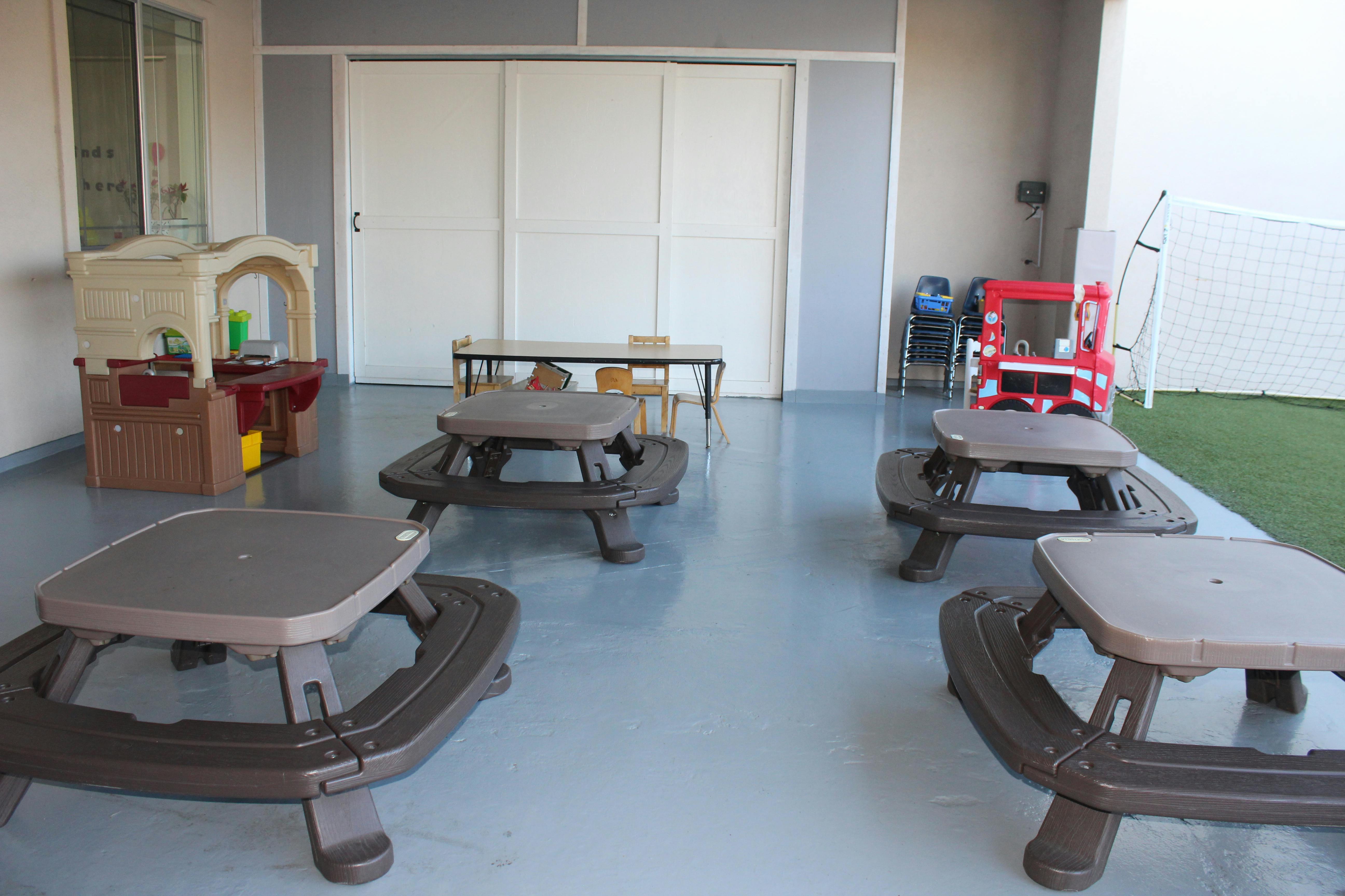 Four small picnic tables and play structures in an outdoor area