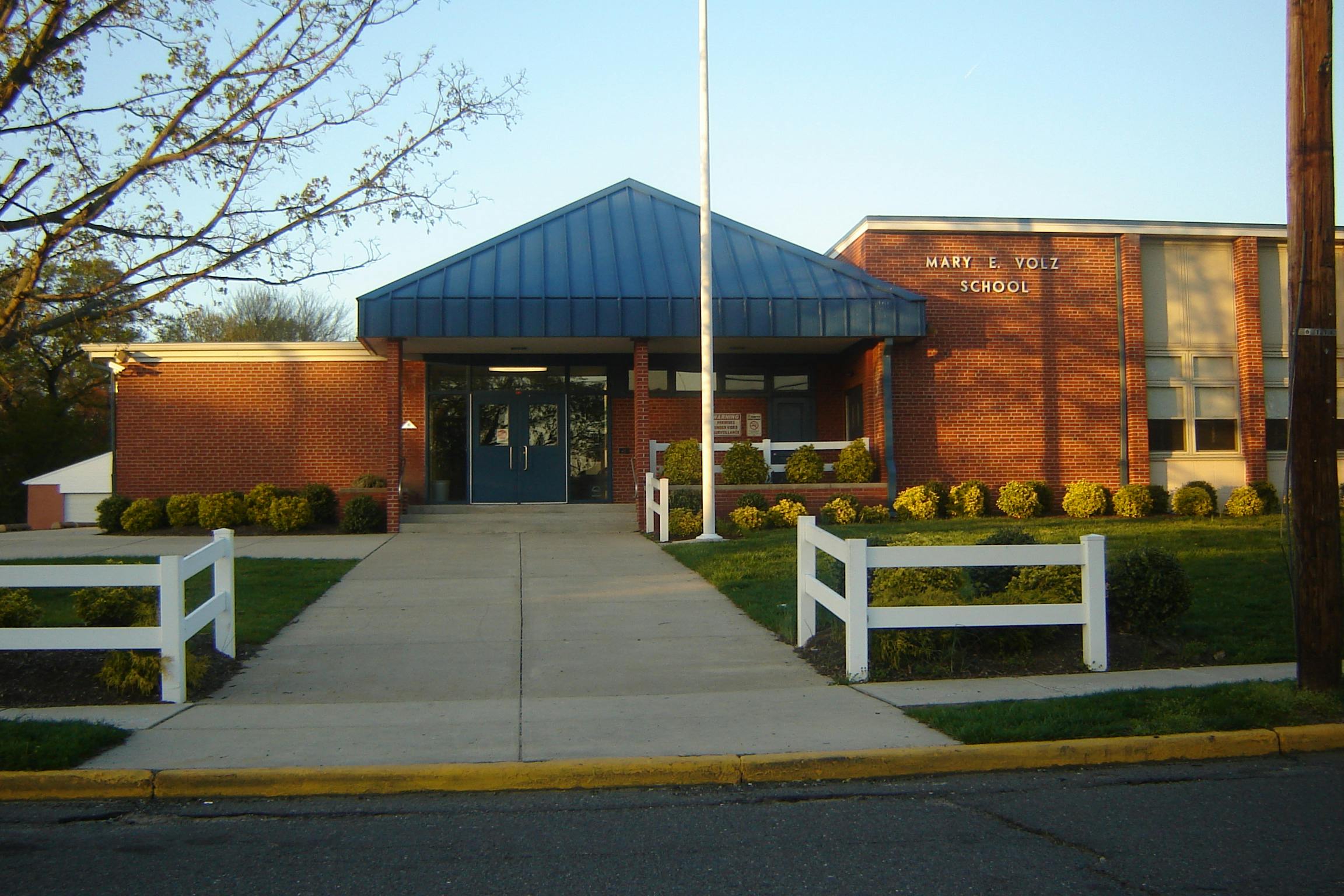 Front entrance of a brick school building with a blue roof