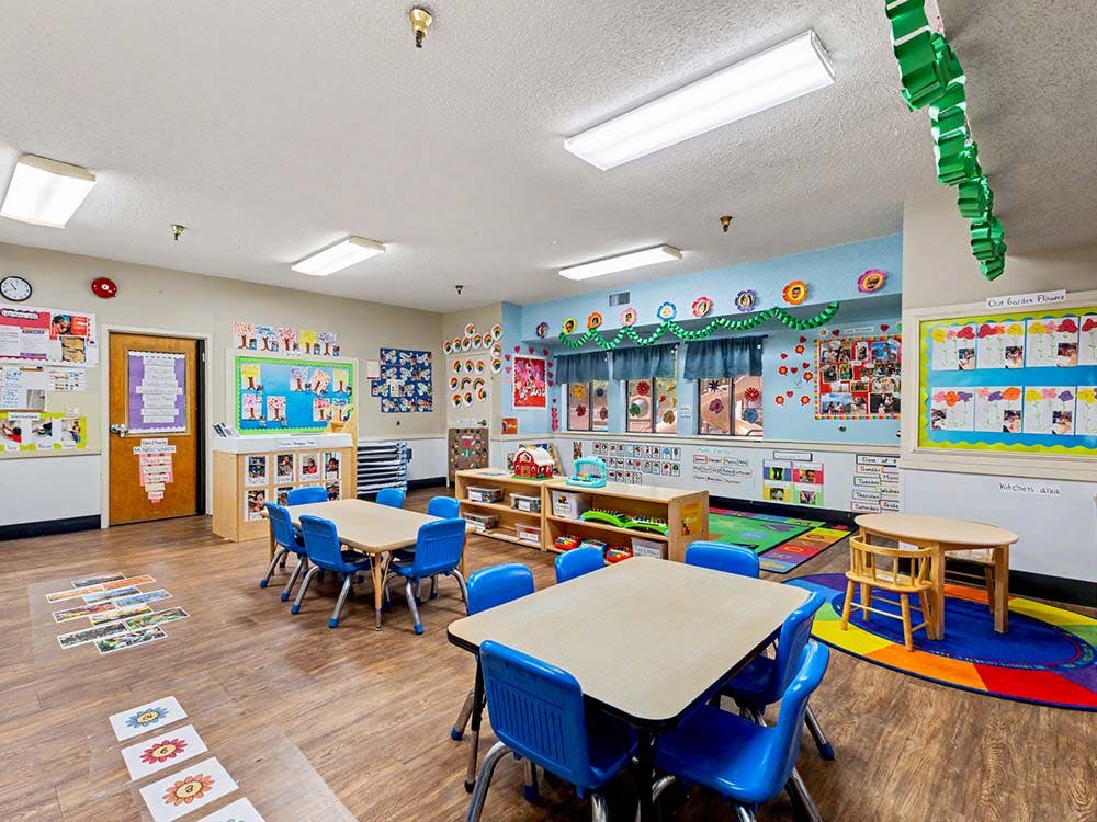 An empty classroom with small tables and chairs