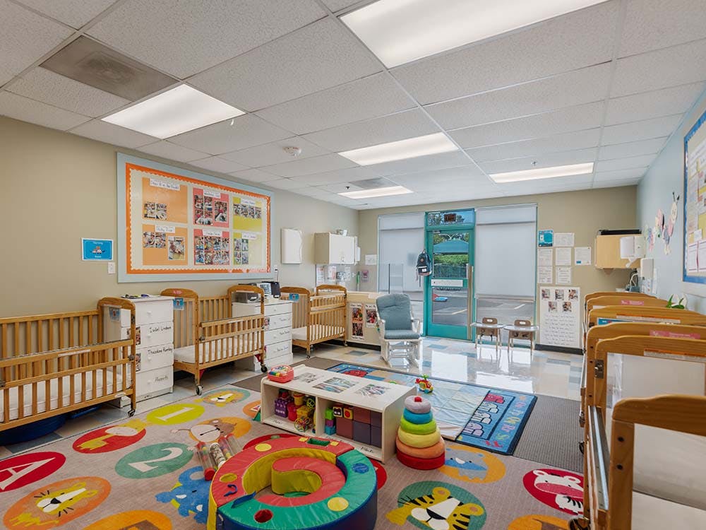 Cribs and colorful playmats in a daycare classroom