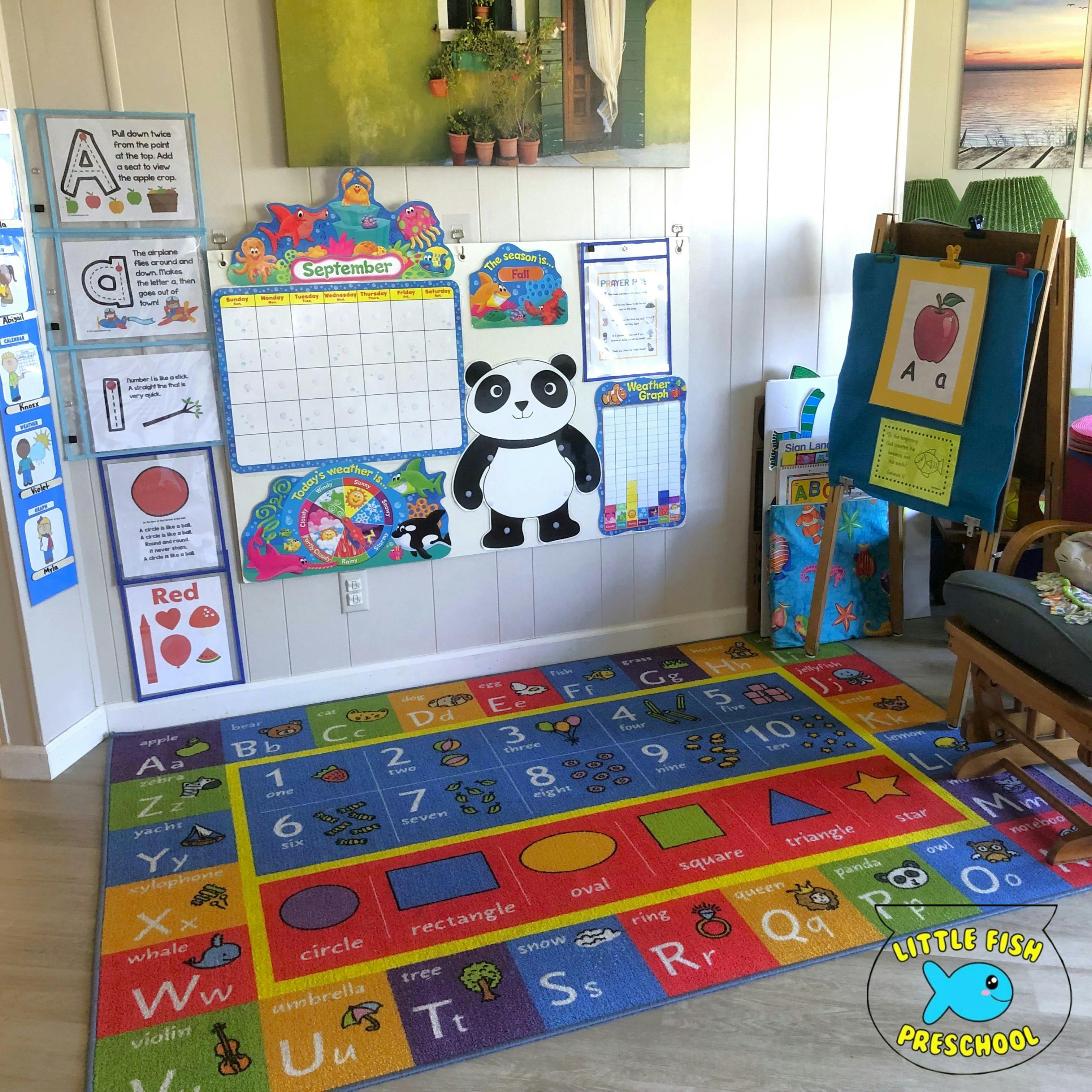 A classroom with alphabet and numbers rug, calendar, weather chart, and a panda cutout