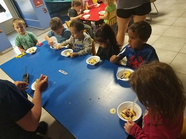 Children eating from bowls at a blue table