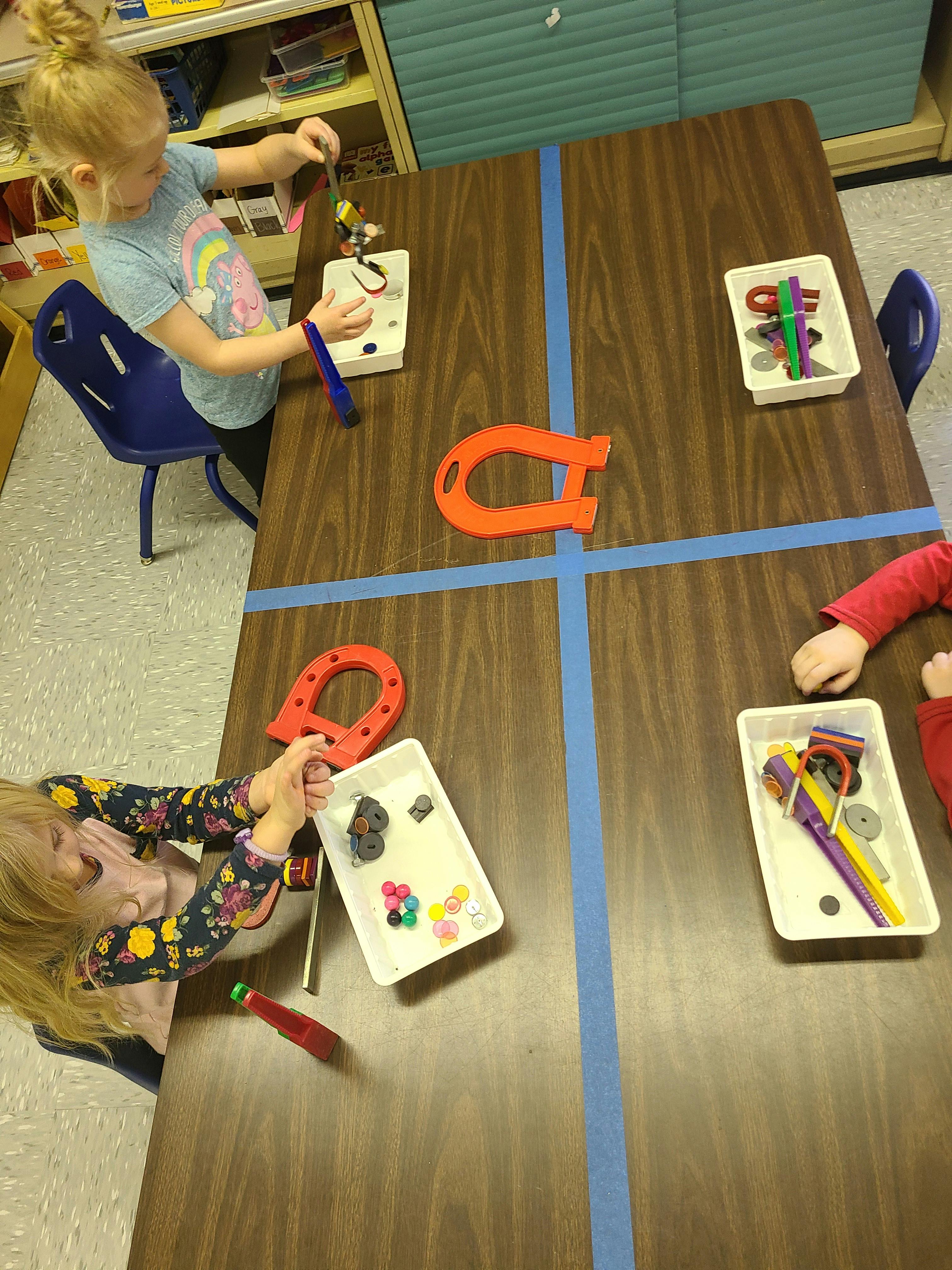 Children playing with magnets and small objects at a table