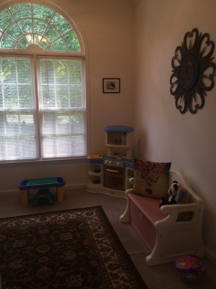 Playroom with toy kitchen, small table, and storage bench near a window