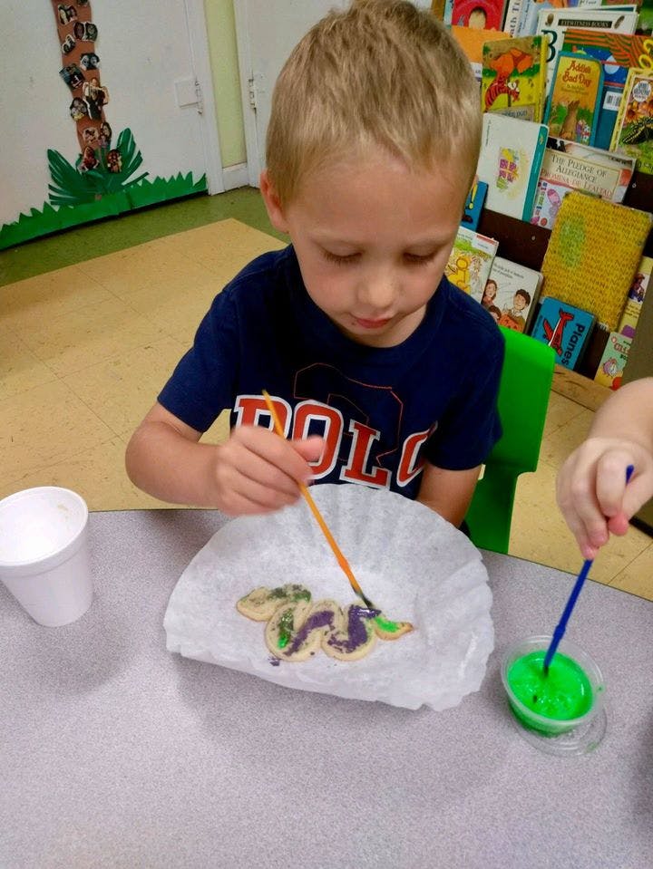 Child painting a cookie with a brush