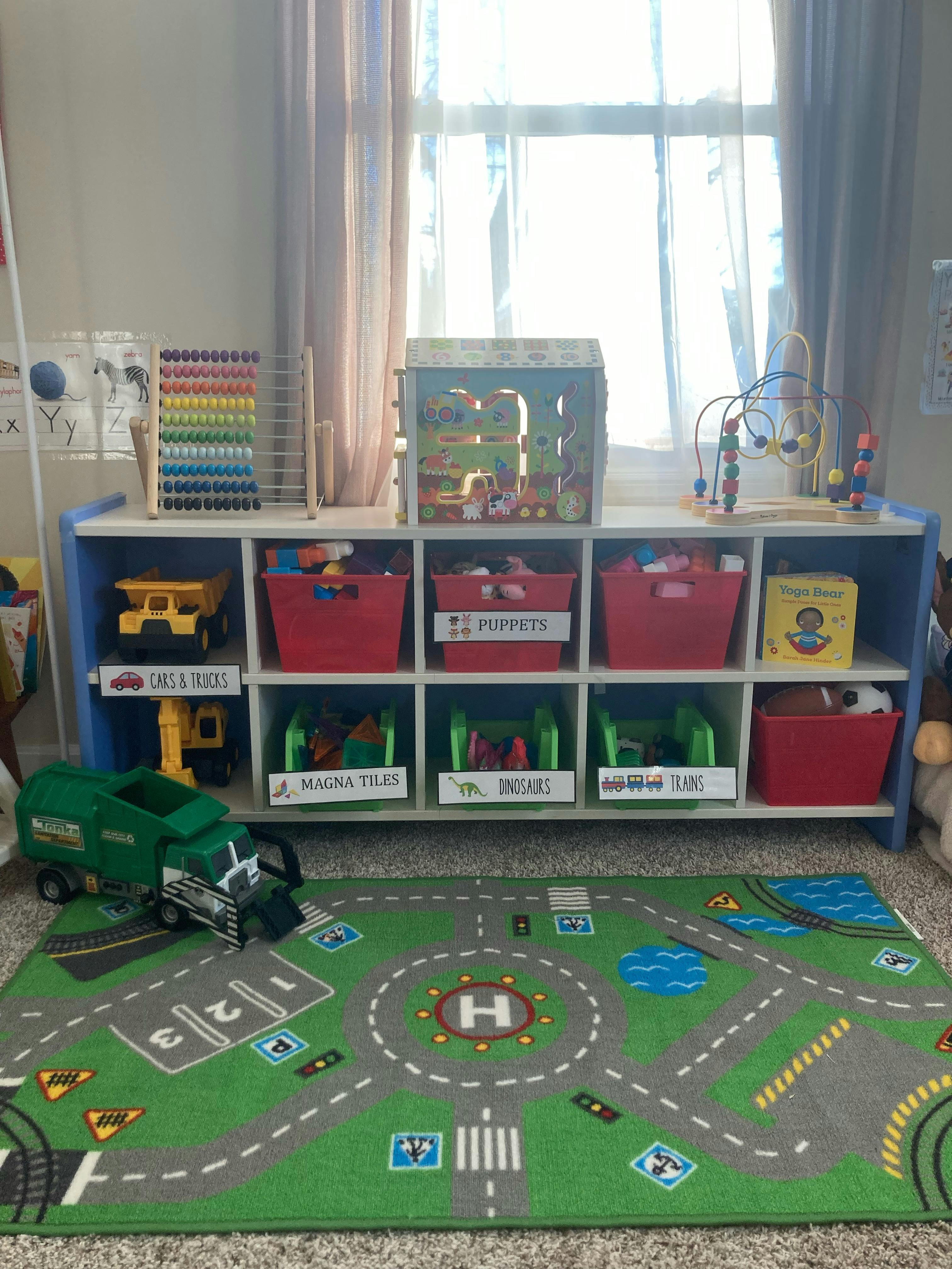 Toy storage unit with bins, toys, and a play rug with a toy truck