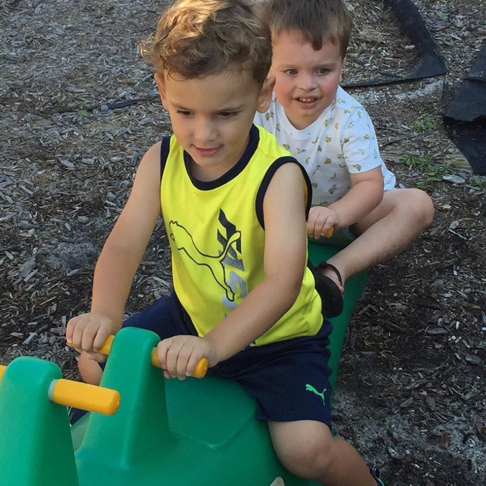 Two children on a green ride-on toy