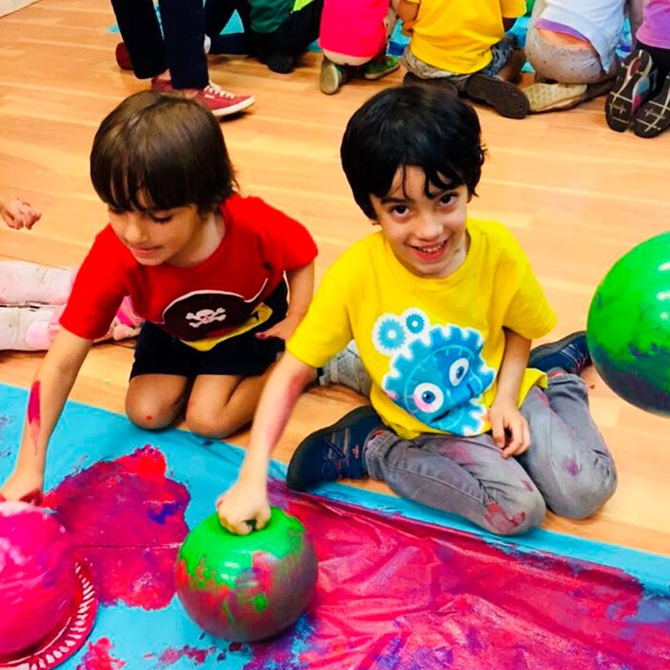 Two children painting with colorful paint on the floor