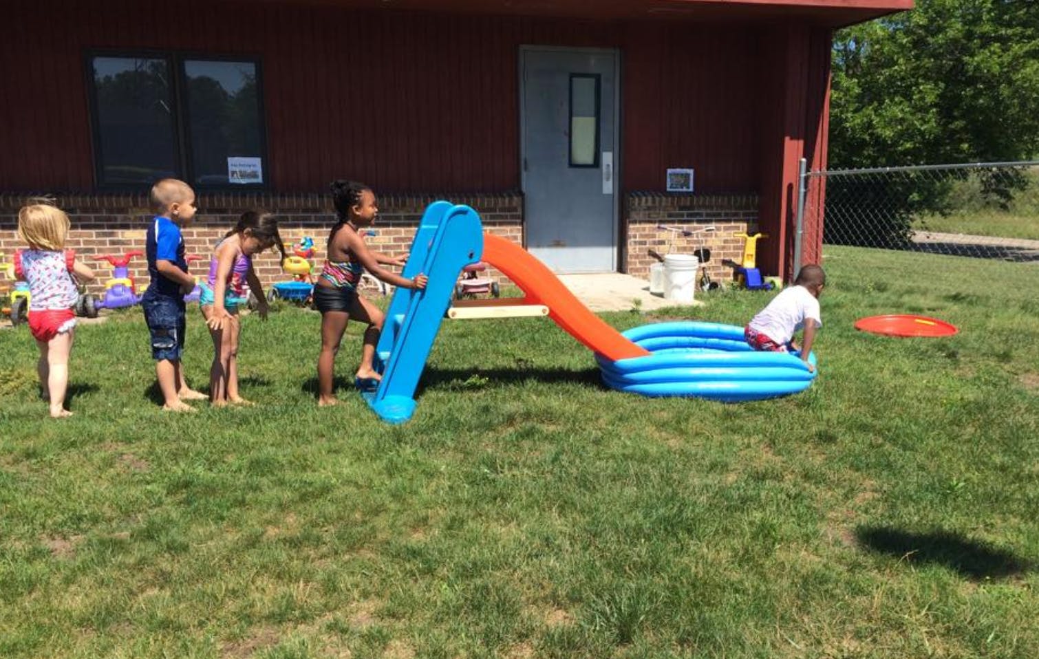 Children playing with a slide and inflatable pool outdoors
