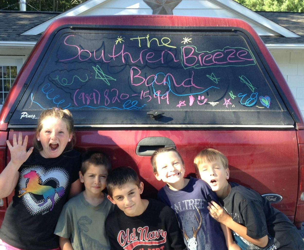 Five children in front of a truck with "The Southern Breeze Band" written on the back
