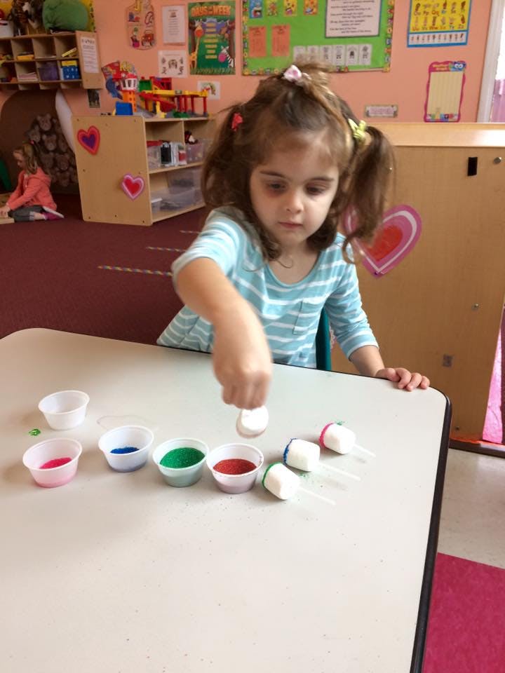 Child playing with small cups and white objects on a table