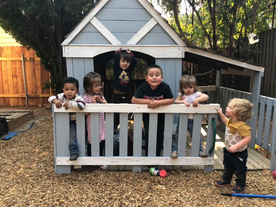 Children playing in and around a small playhouse