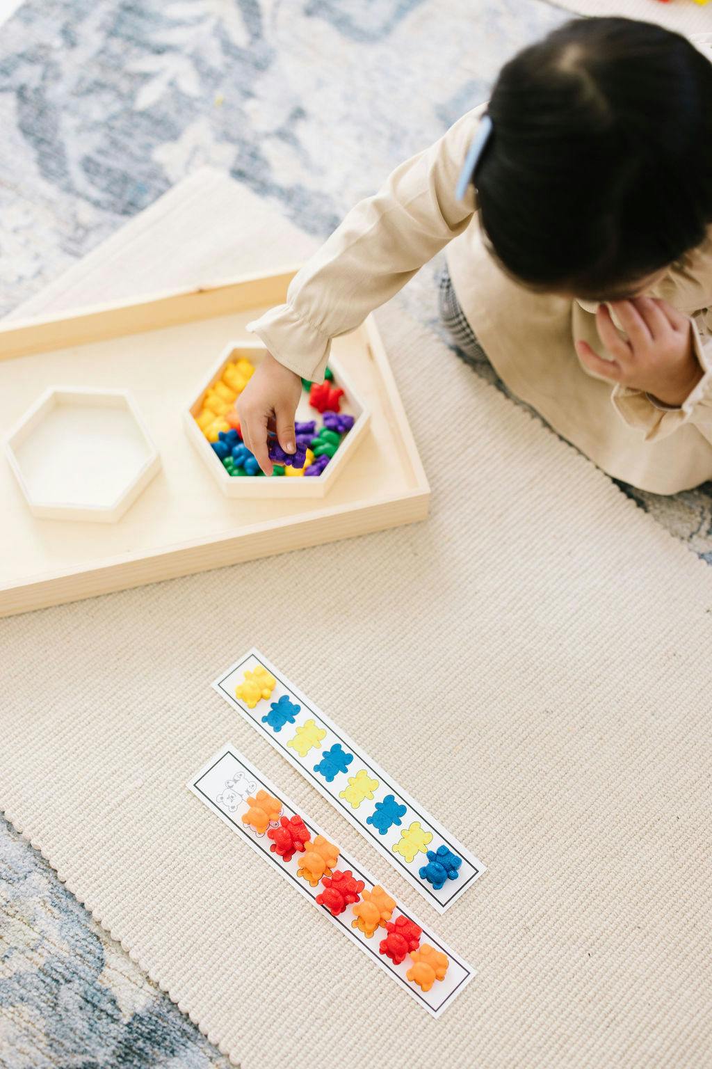 Child playing with colorful bear-shaped counters and pattern cards