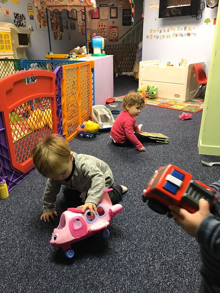 Two children playing with toys on a carpeted floor in a playroom
