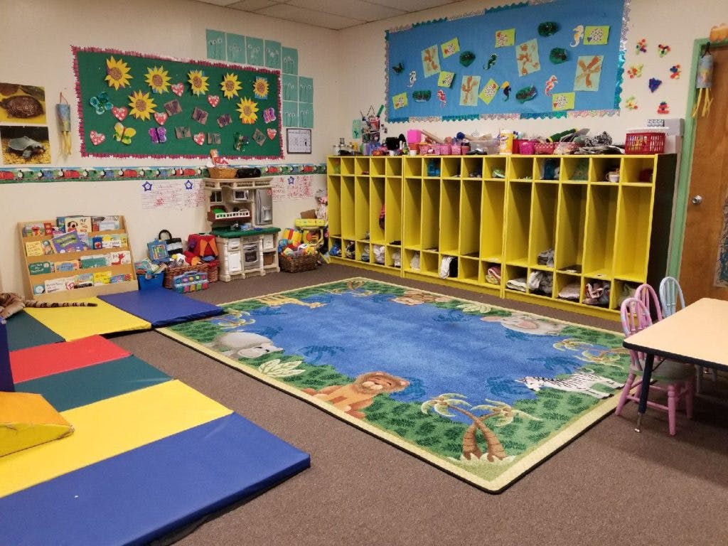 Classroom with colorful rug, cubbies, and play mats