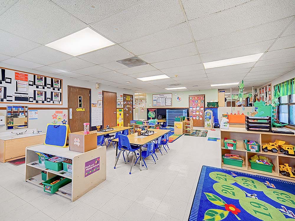 Classroom with child-sized tables and chairs, toys, and learning materials