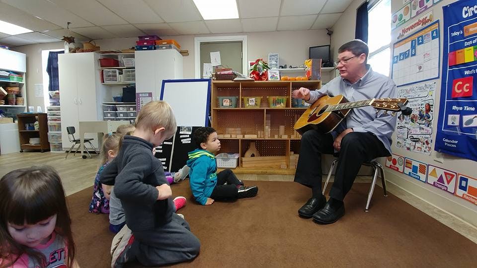 Person playing guitar for children in a classroom
