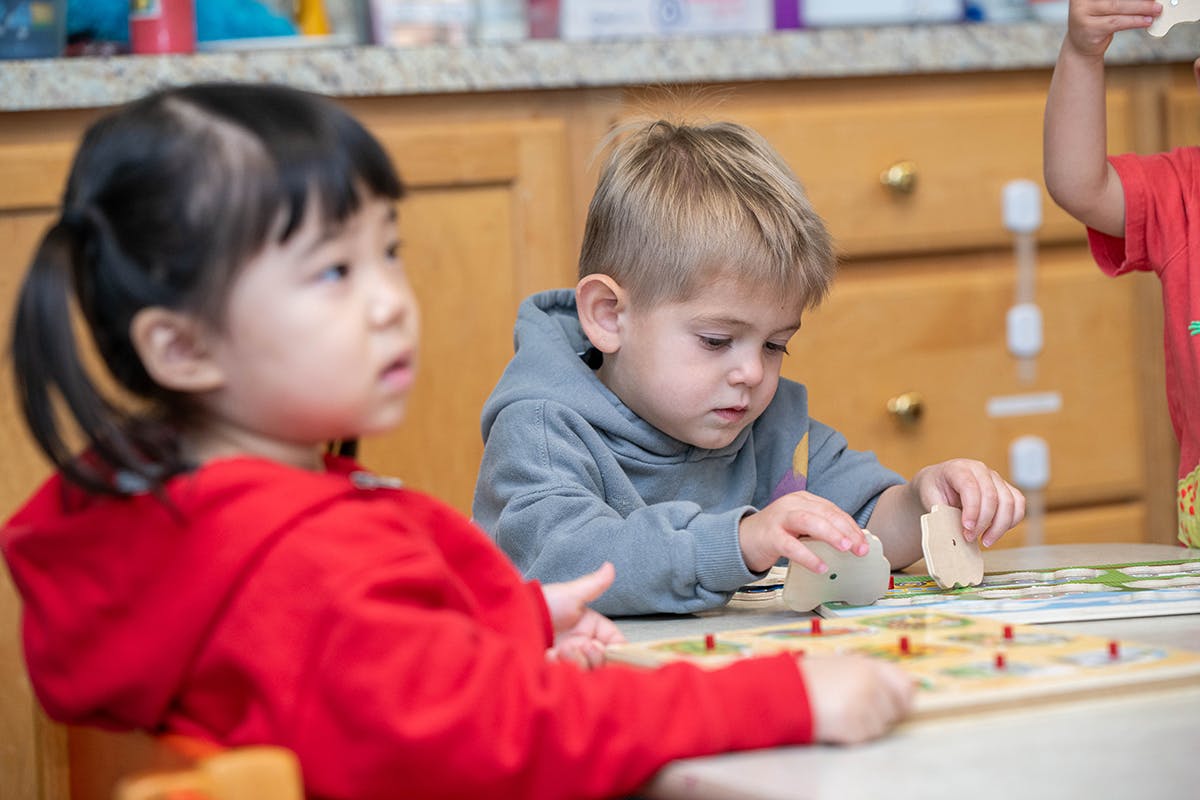Two children playing with a board game at a table