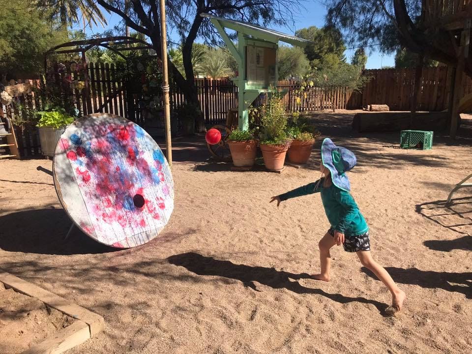 Child throwing a ball at a painted target