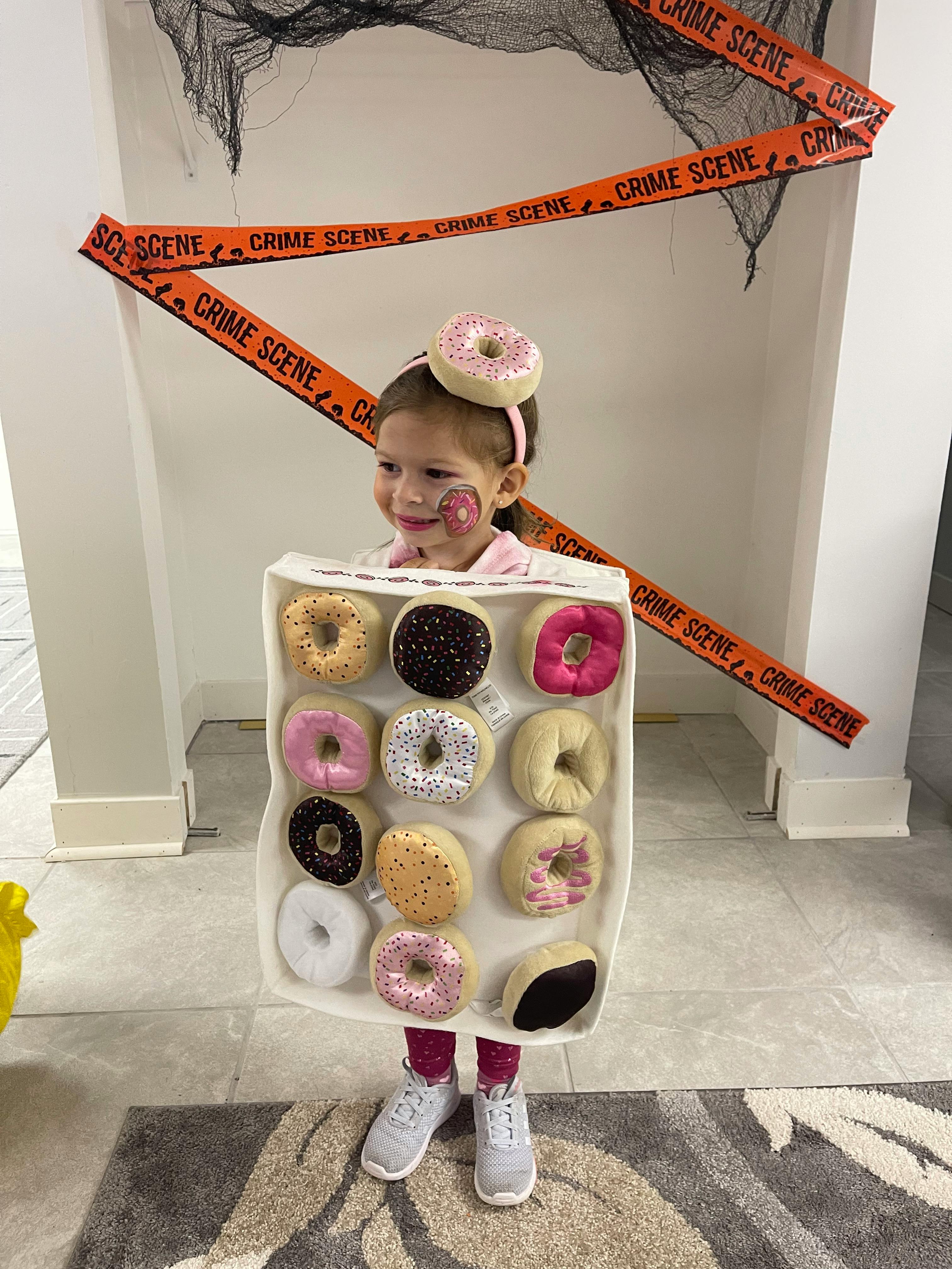 Child in a donut box costume with a donut headband