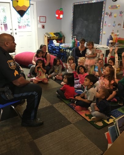 Police officer speaking to a group of children and adults in a classroom