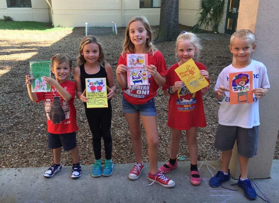 Five children holding up drawings or artwork