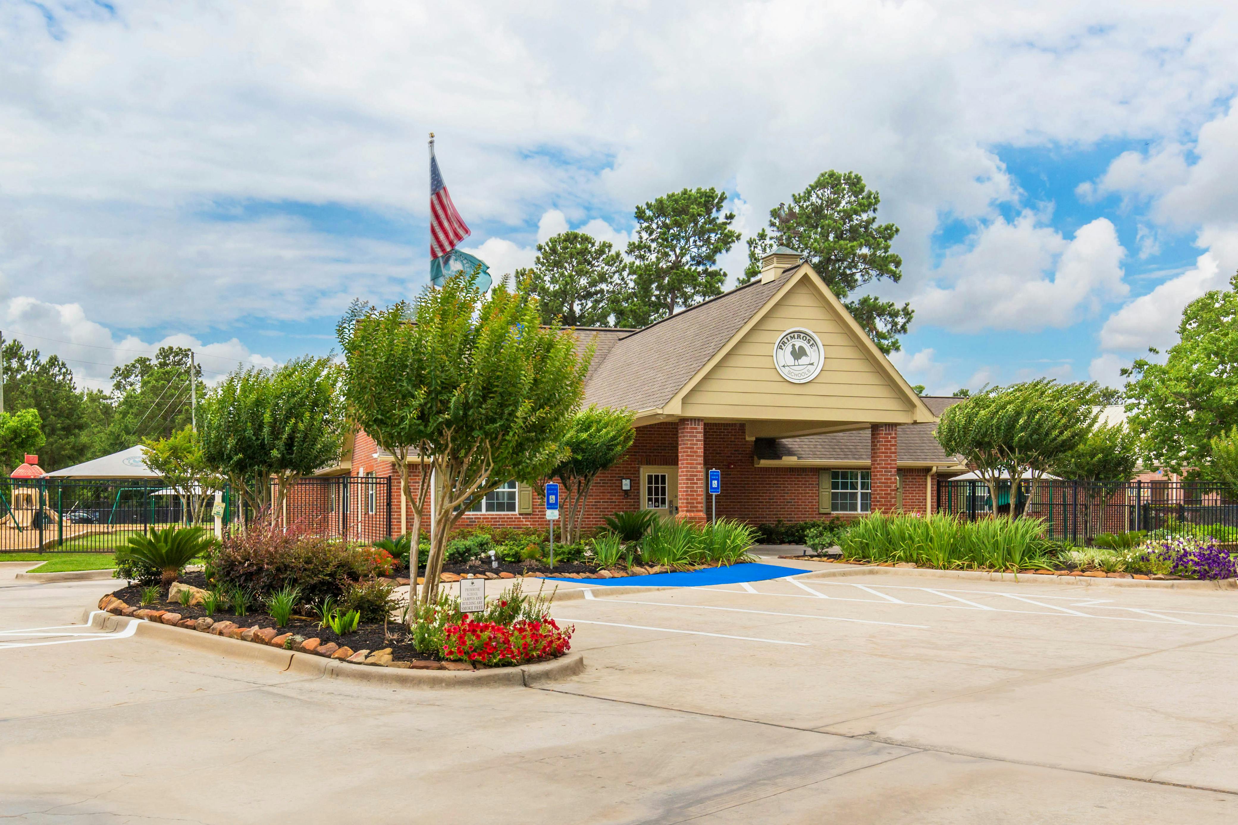 Brick building with a parking lot and landscaped islands with flowers and trees