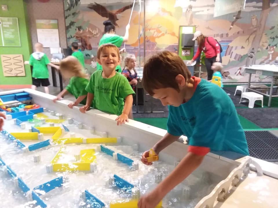 Children playing in a water table with yellow and blue toys