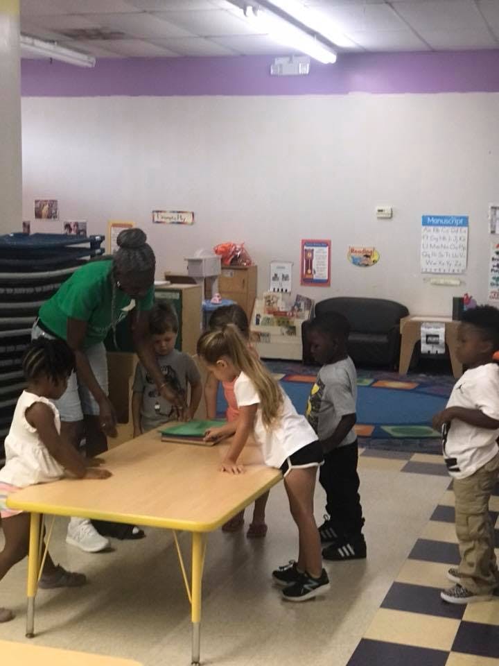 Adult and children gathered around a table in a classroom