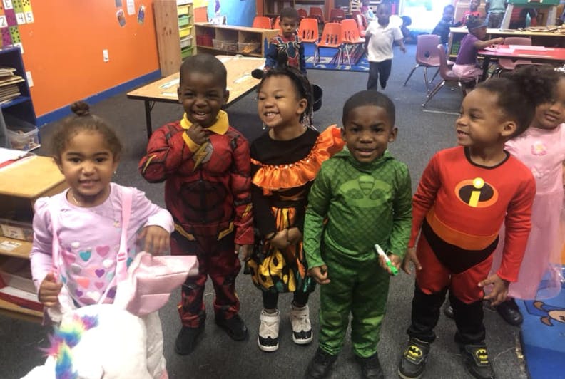 Five children in costumes standing in a classroom