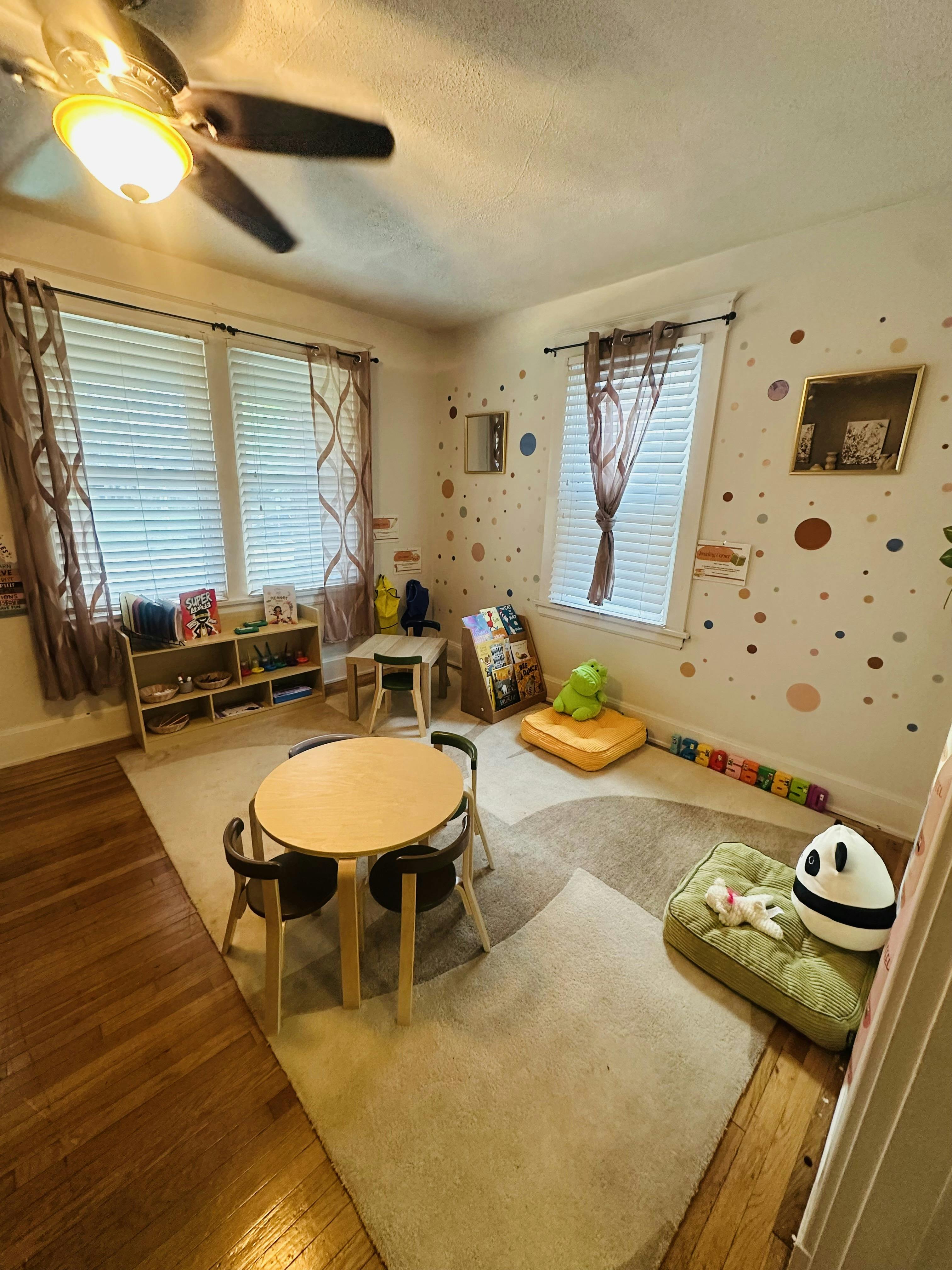 Playroom with tables, small chairs, bookshelves, and floor cushions