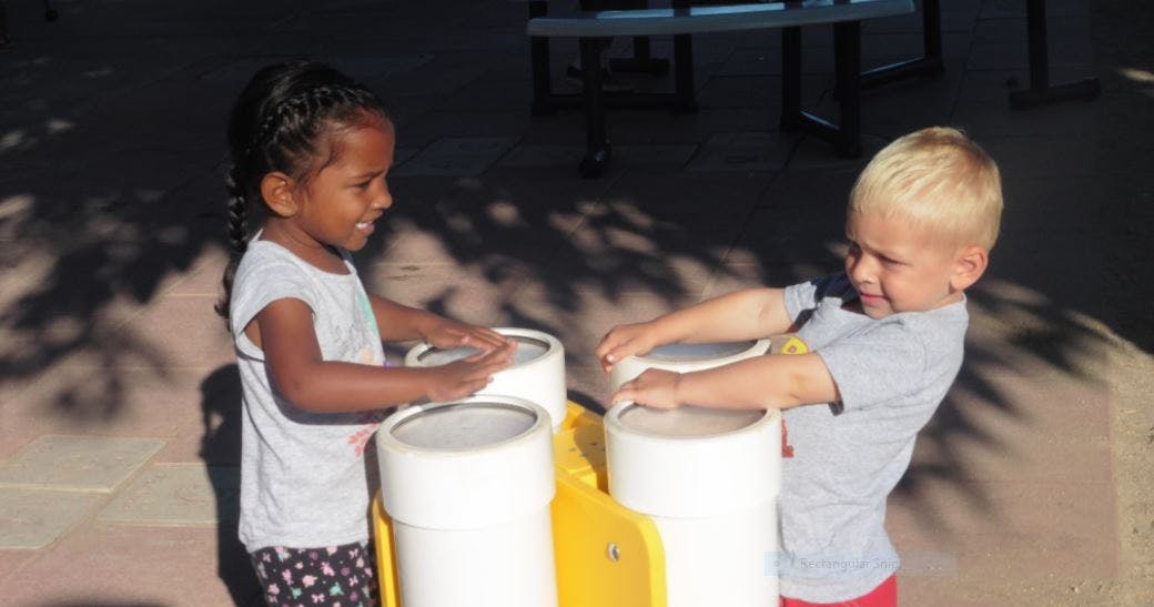 Two children playing with drums
