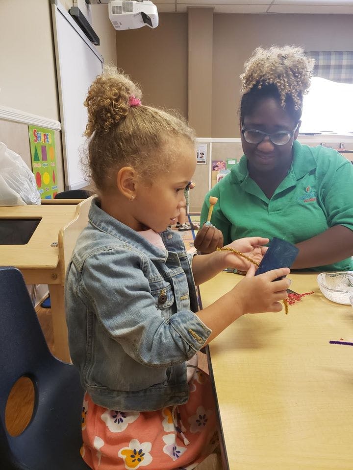 Child and person crafting in a classroom