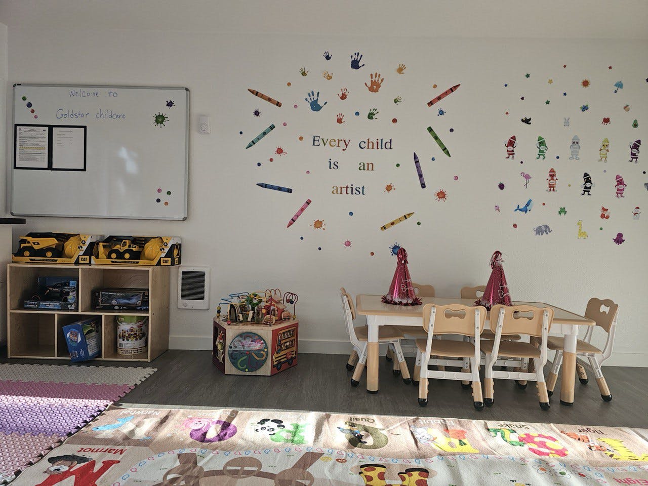 Classroom with small tables and chairs, toys, and a whiteboard