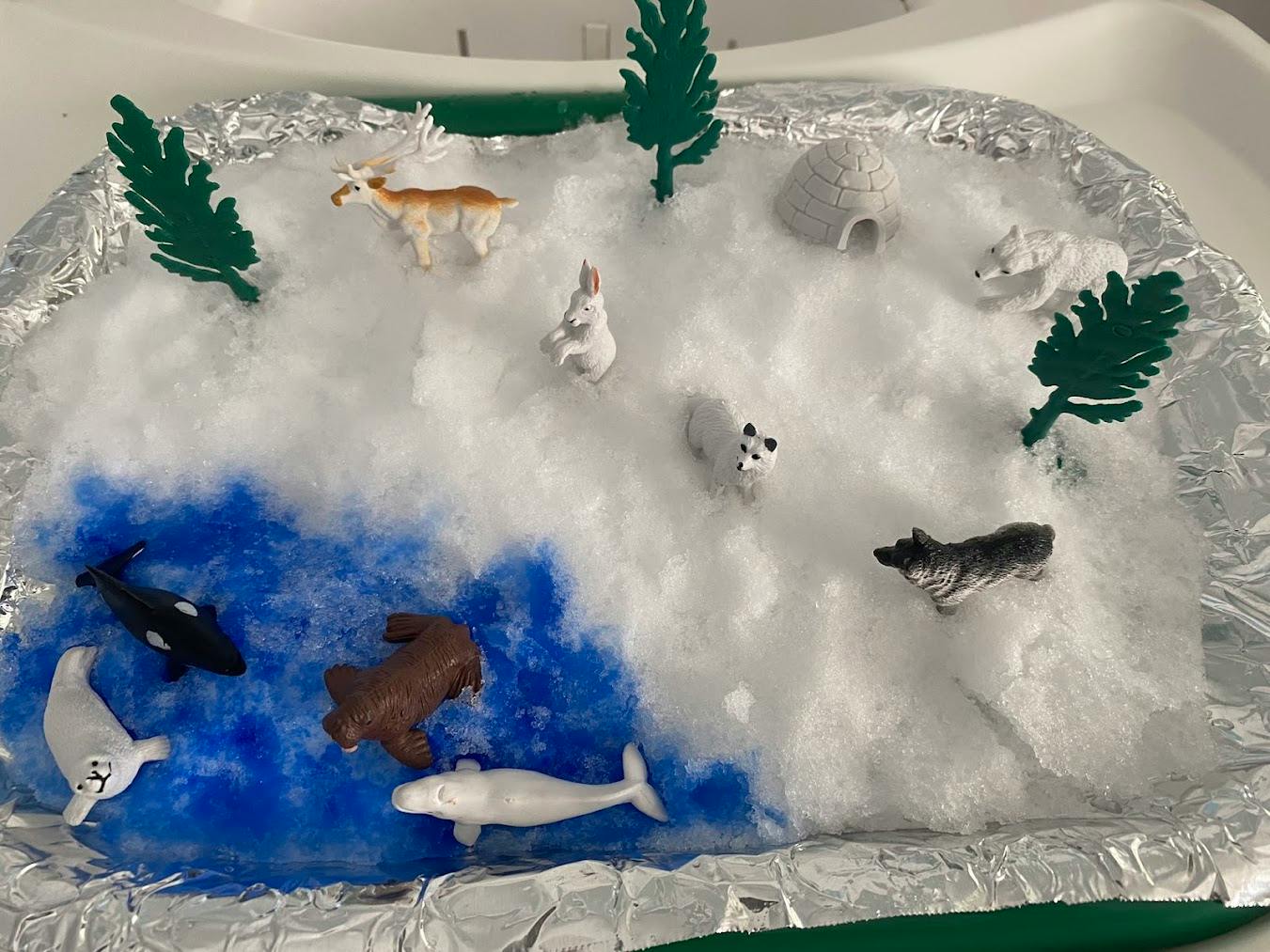 Diorama of arctic animals and an igloo on a snowy landscape with water surface