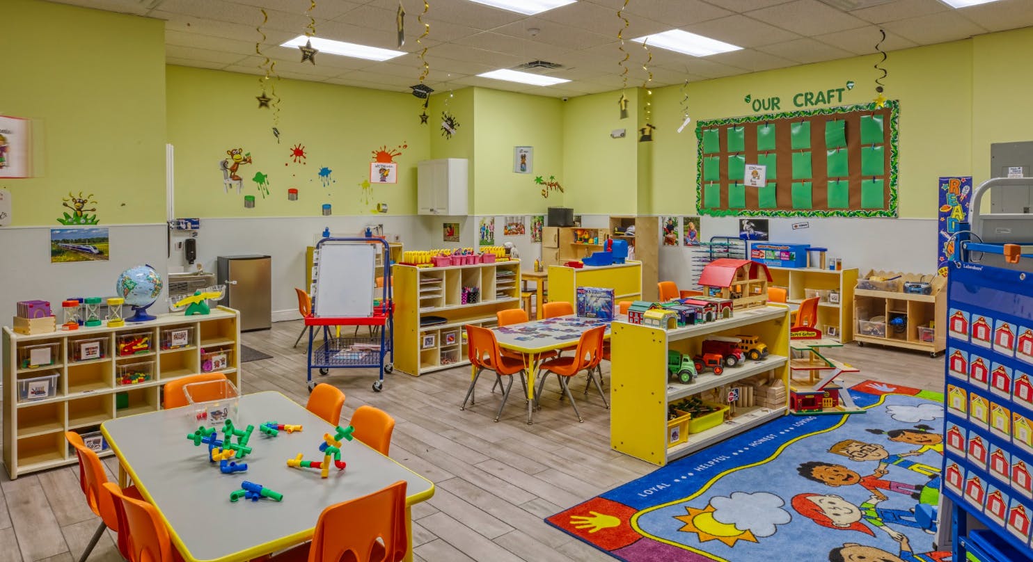 A colorful empty classroom with small tables, chairs, and learning materials
