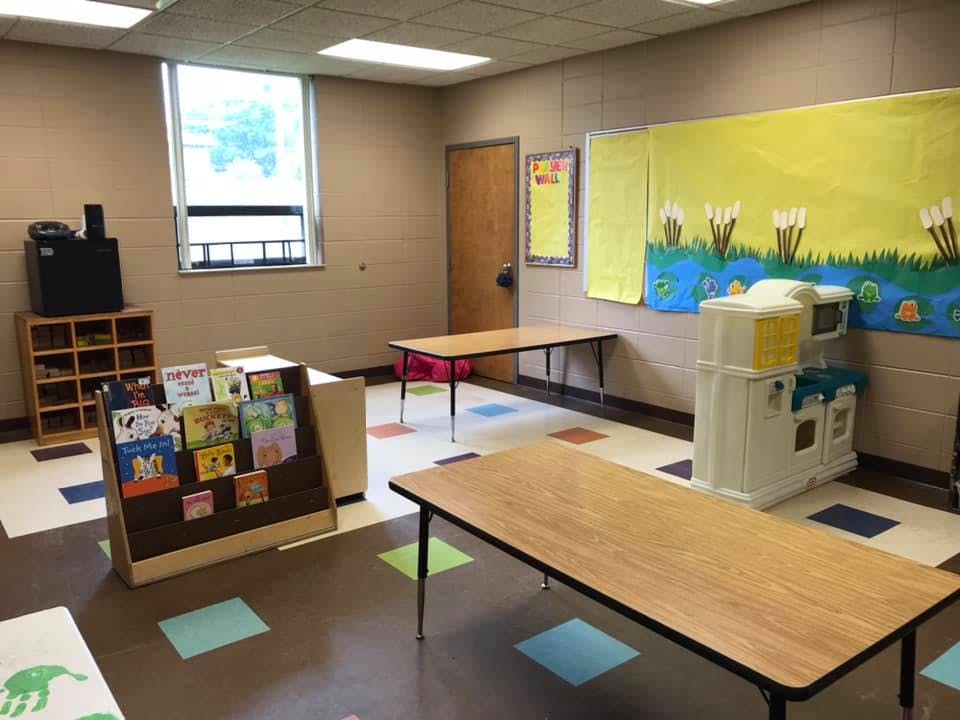 Empty classroom with tables, chairs, and a bookshelf