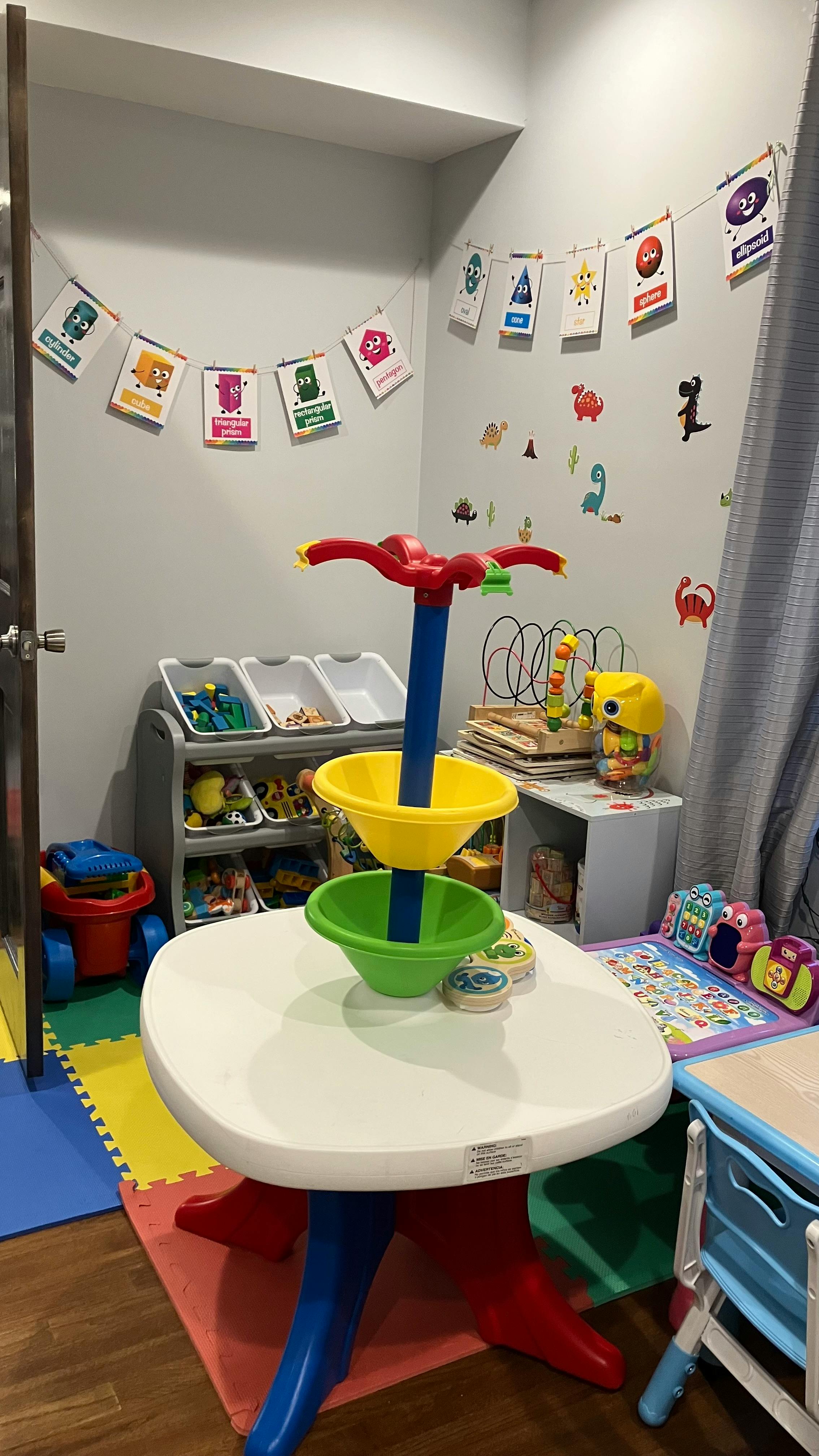 Playroom with a white table, colorful toys, and wall decorations