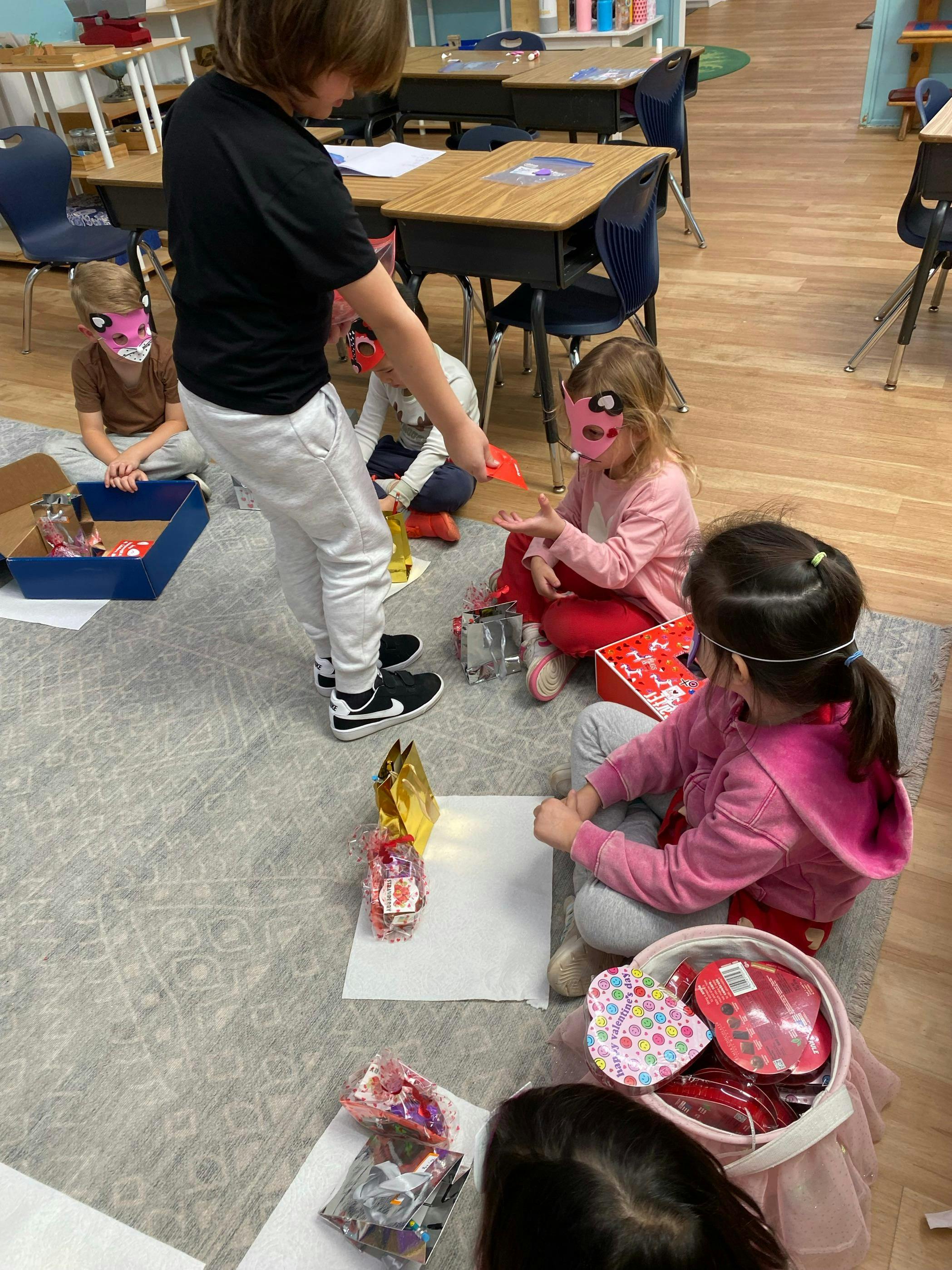 Children in cat masks exchanging small gifts in a classroom