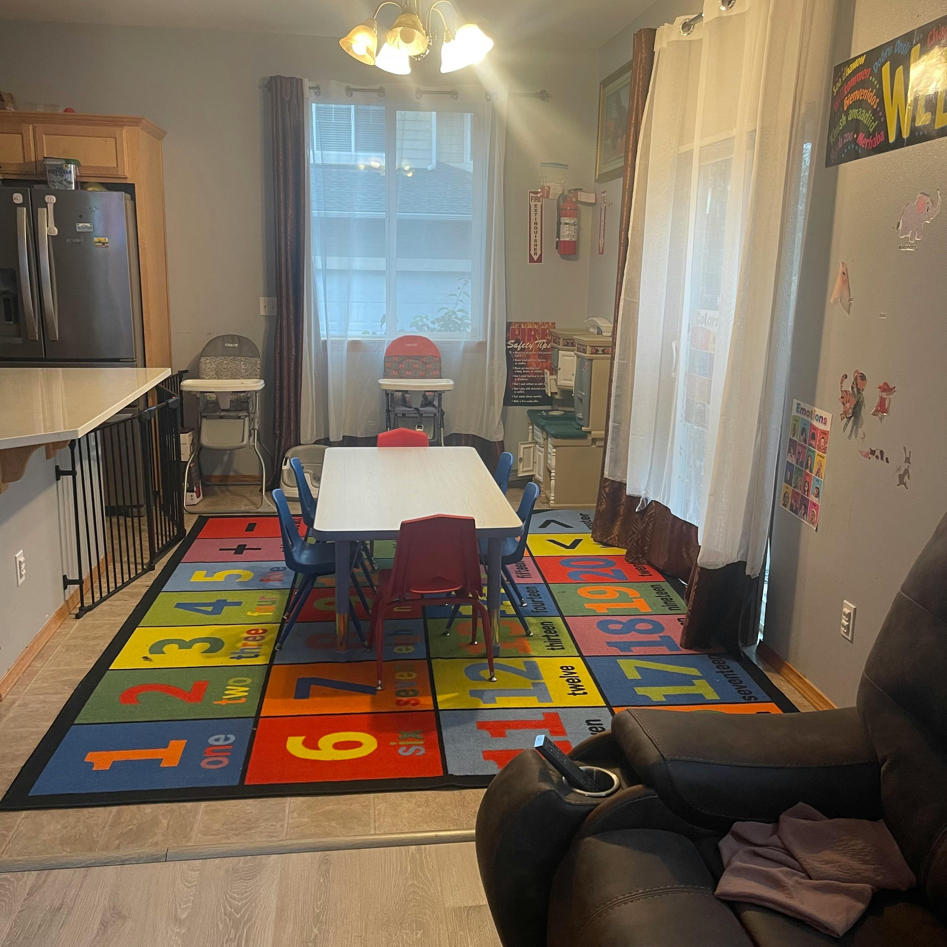 Children's play area with a table, chairs, and a colorful number rug