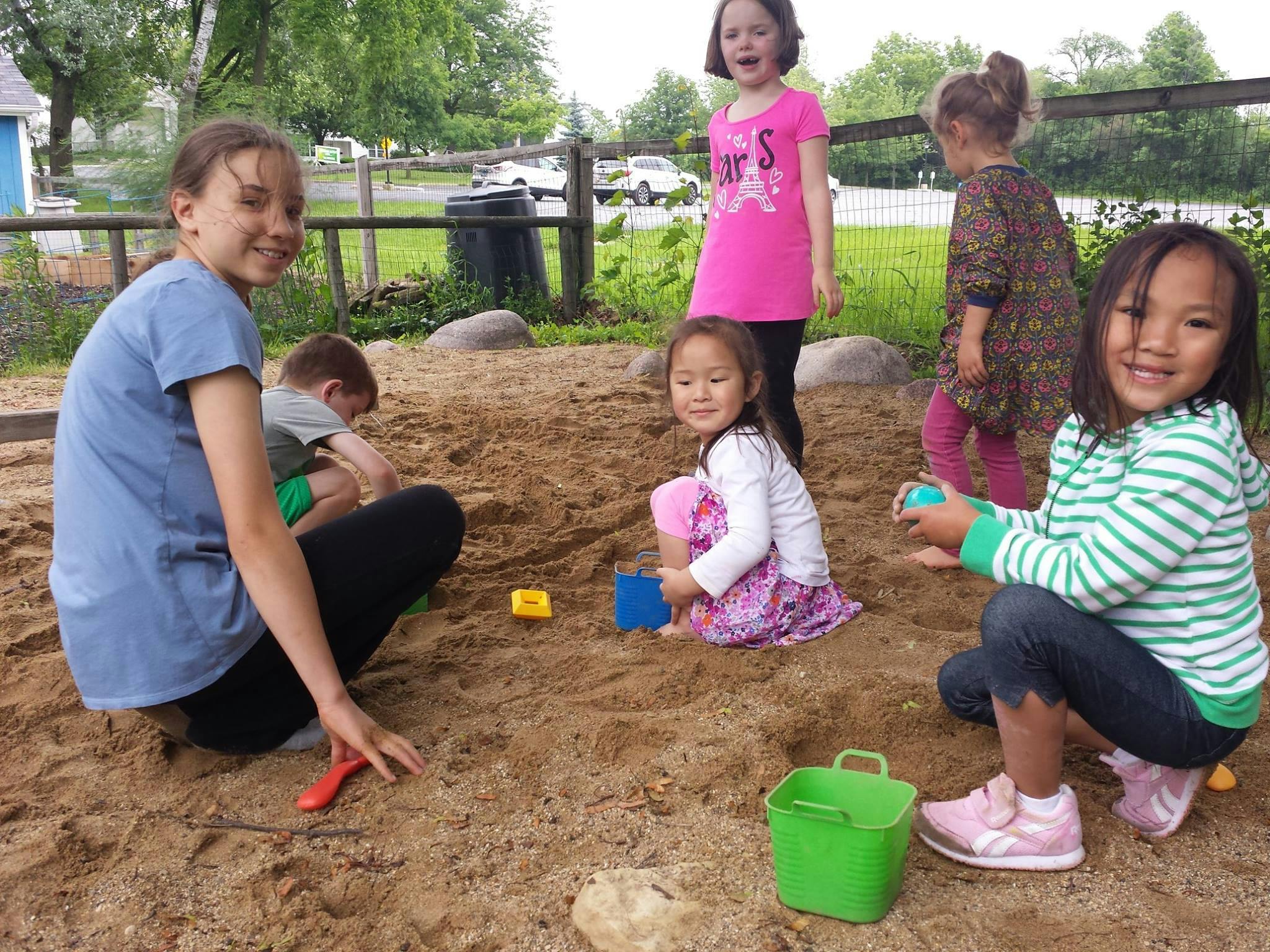 Children playing in a sandbox with toys