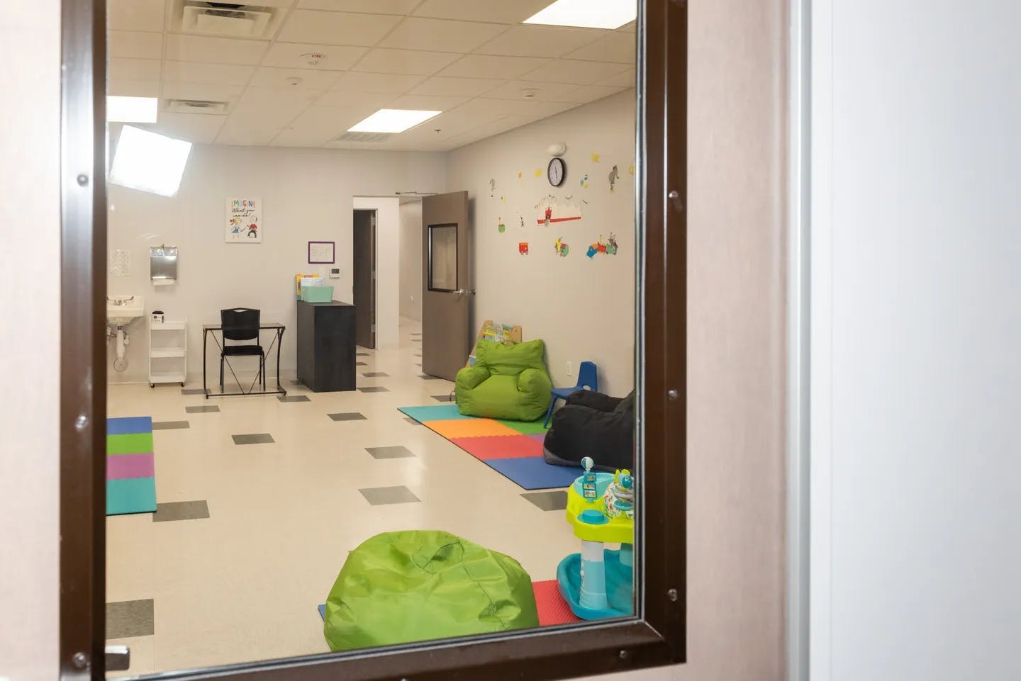 Room with beanbag chairs and colorful mats viewed through a window