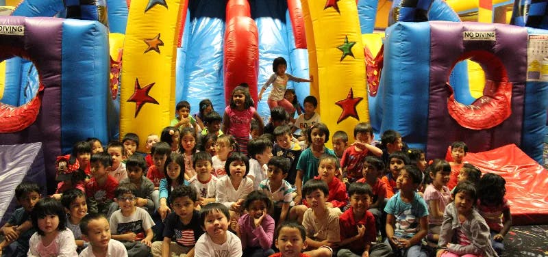 Group of children sitting in front of an inflatable bounce house
