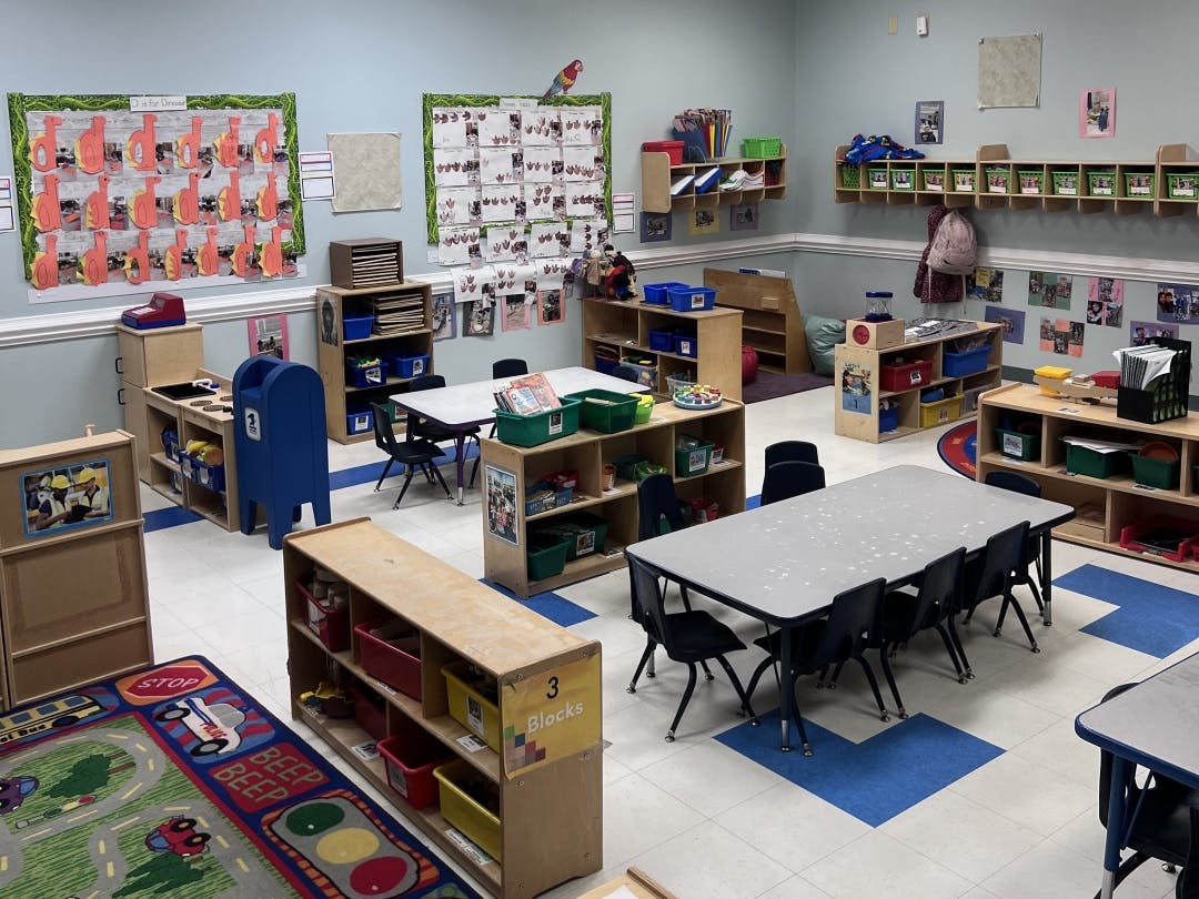 A colorful preschool classroom with tables, chairs, shelving, and decorations
