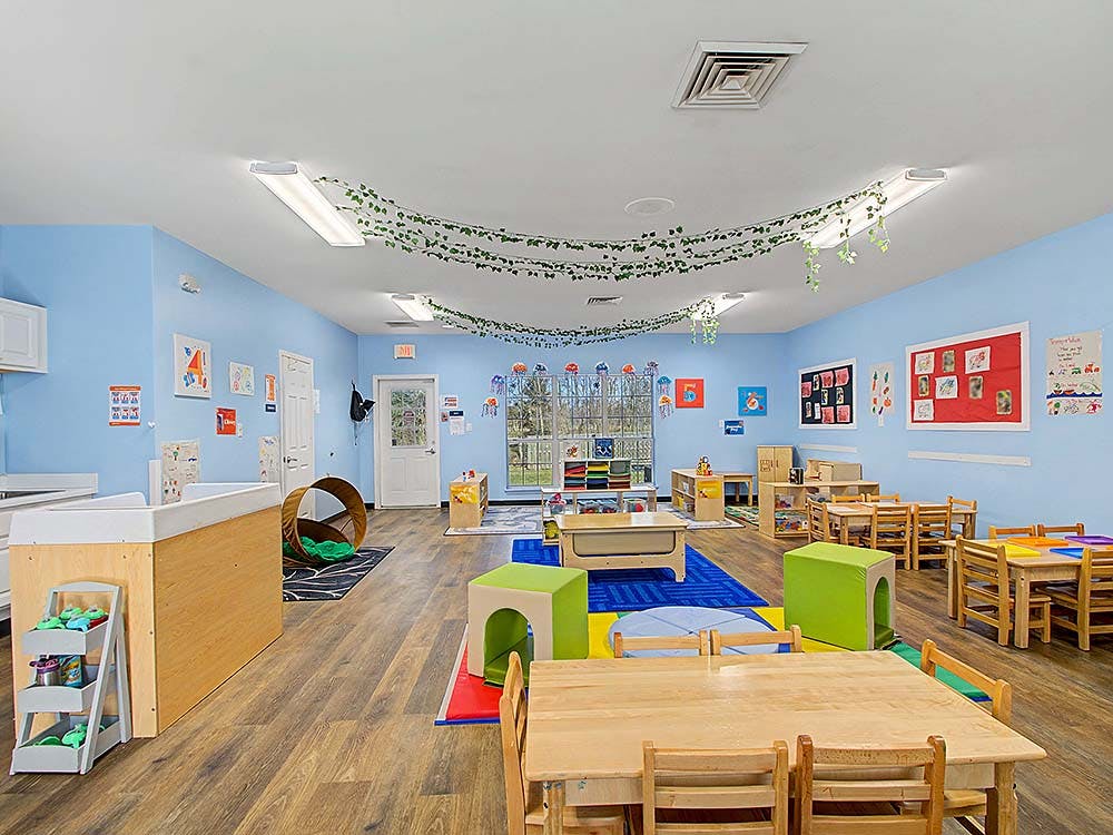 An empty early childhood classroom with small tables and chairs