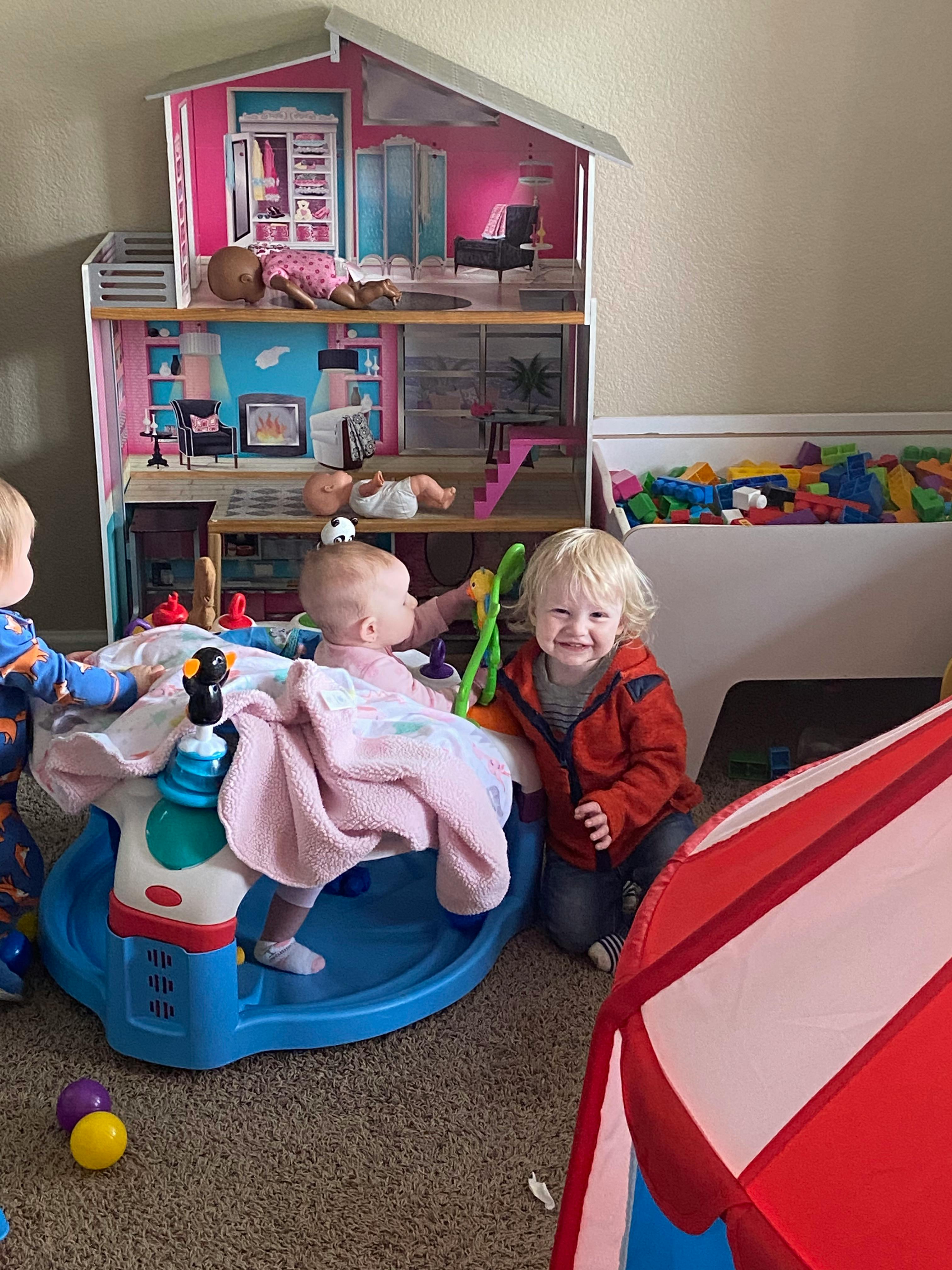 Children playing with a toy house and activity center