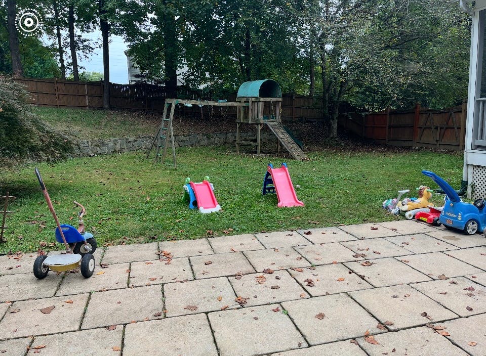 Backyard with playset, two slides, and ride-on toys