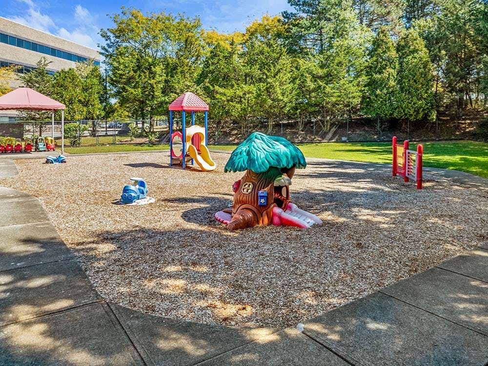 Playground with swings, slides, small ride-on toys, and shaded areas