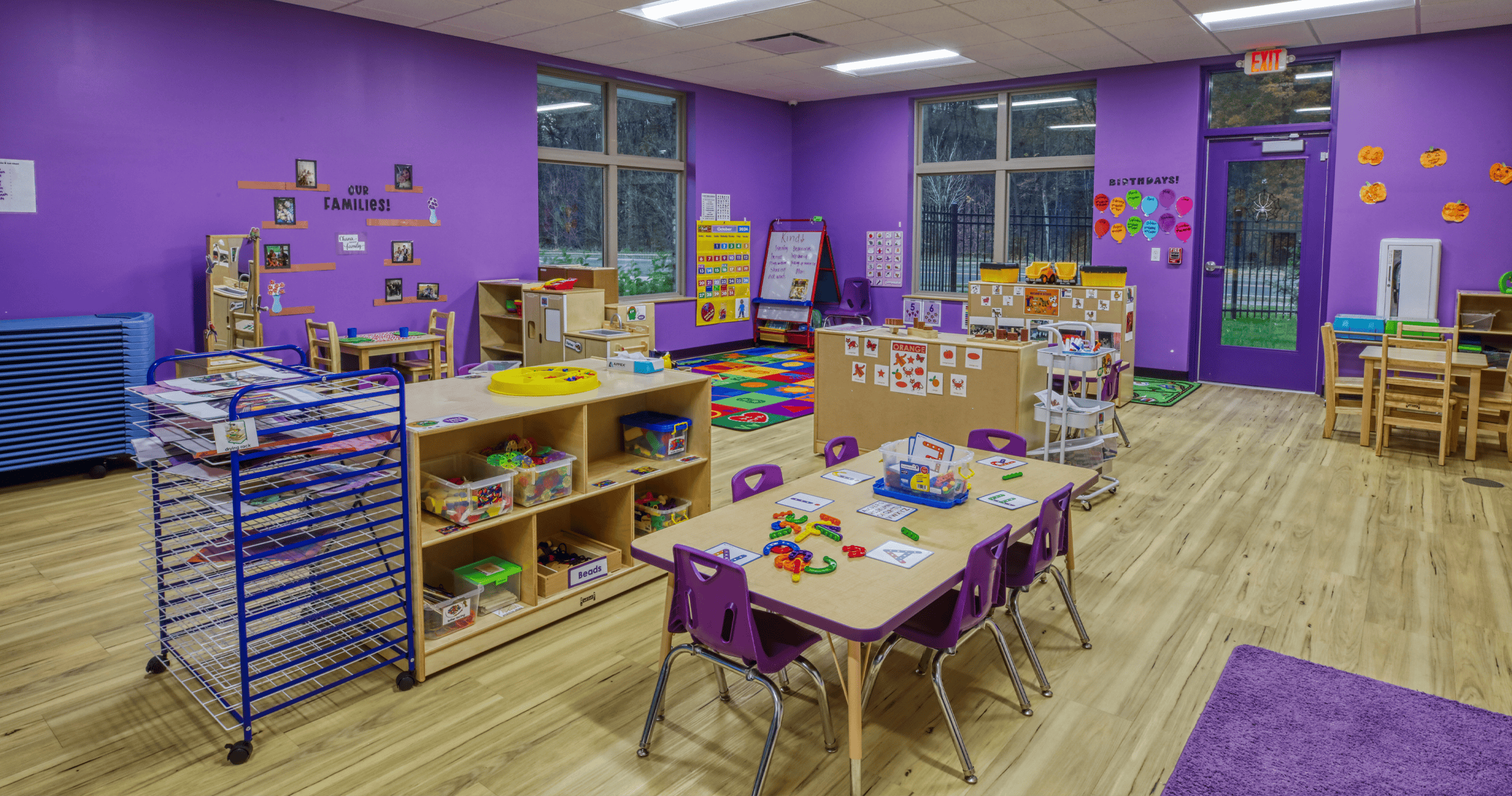 Colorful classroom with purple walls, tables, chairs, and learning materials
