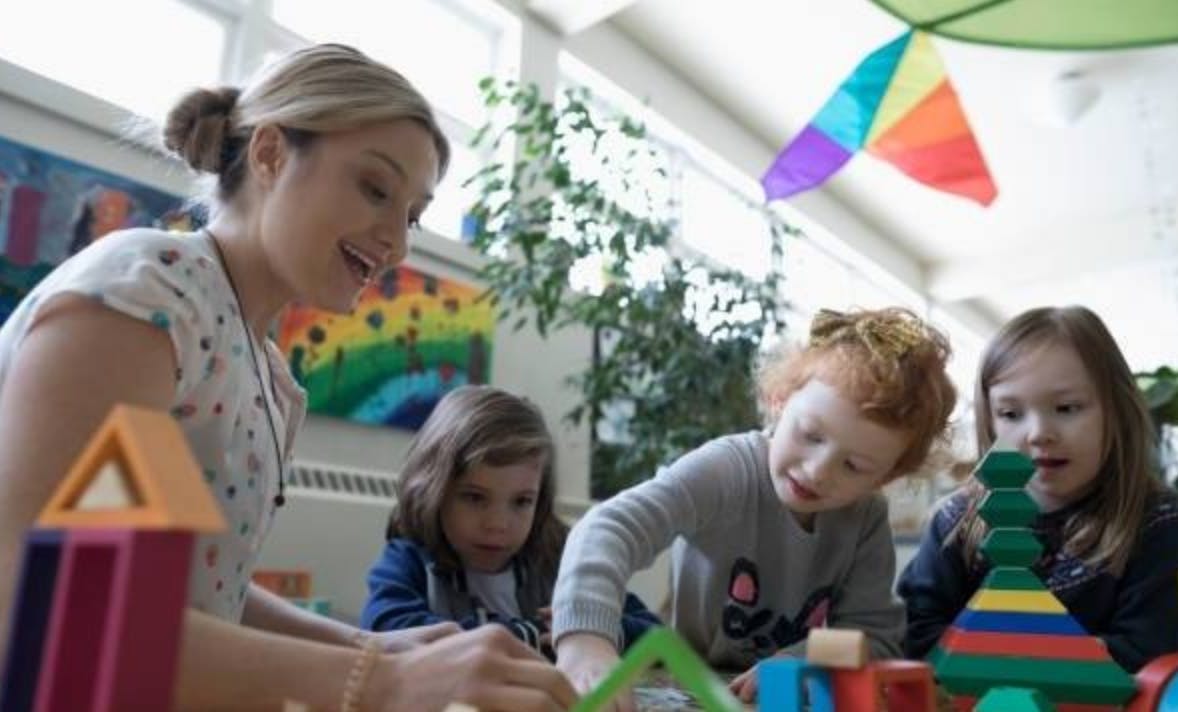 Adult and three children playing with colorful building blocks